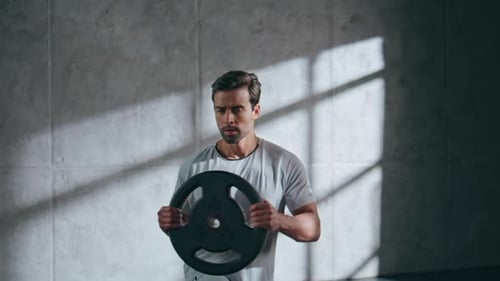 Motivated Athlete Lifting Weight Plate in Gym Club Closeup Bodybuilder Training