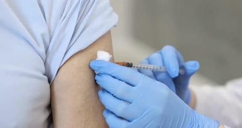 Nurse in medical gloves vaccinating man against blurred background, closeup. Camera moving forward