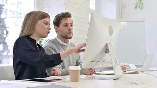 Attraktives Kreativteam, das am Desktop diskutiert und arbeitet