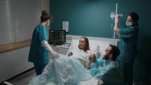 Schwangere Frau bringt Baby mit Ehemann und Hebammen im Krankenhaus zur Welt