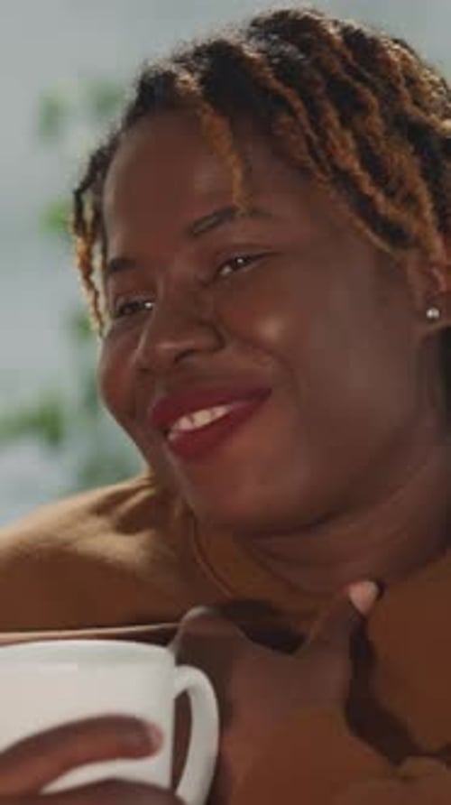 Mujer afroamericana sonríe conmovida por una película romántica