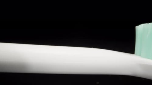 Squeezing toothpaste on a toothbrush. Dolly slider extreme close-up.