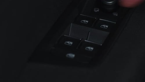 Close-up pressing the up and down window buttons on a car.