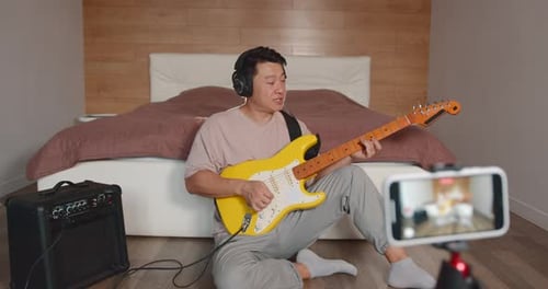 Man Sits and Plays Yellow Electric Guitar