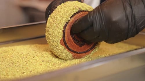 Pistachio croissant donut being decorated rolling over cream and pistachio dripping