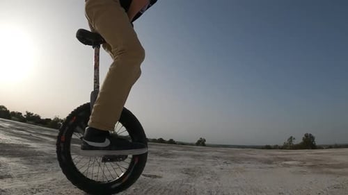 Young Adult Jumps on Unicycle Outdoors