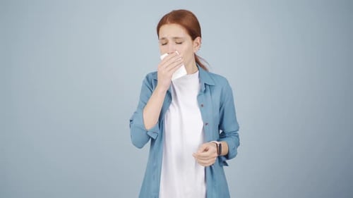 Woman covering her mouth and nose while coughing.