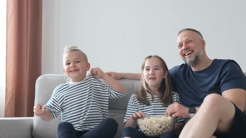 Happy Family Watching and Eating Popcorn on Sofa