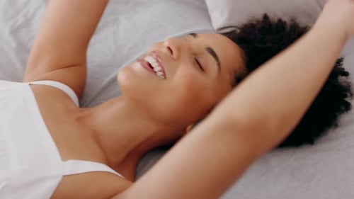 Woman Receives Headphones While Lying on Bed Smiling