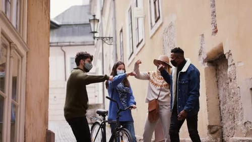 Young multi ethnic friends greet each other in town during coronavirus pandemic
