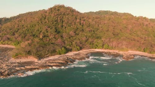 Aerial tilt reveal flight of Costa Rica jungle and bay with rough breaking waves