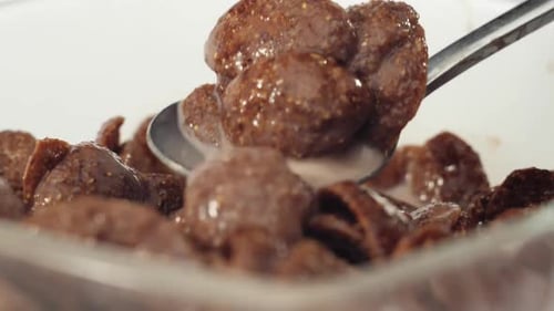 Spoon Scooping Chocolate Cereal into Bowl of Milk