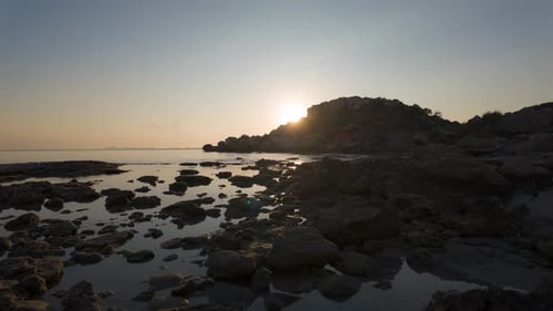 Sun Setting Behind Rocky Beach Outcrop