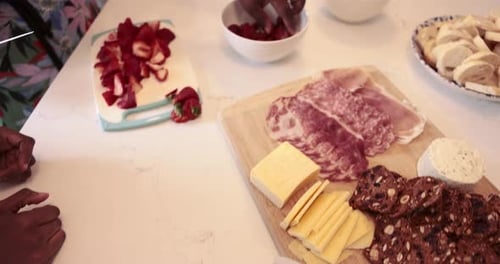 Young women prepare fruit charcuterie and flatbread pizza in a kitchen