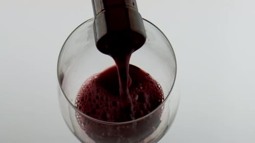 Pouring Red Wine into Glass on White Background