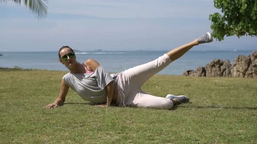 Young woman exercising in seaside garden for fitness and strength on a sunny day
