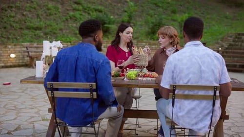 Friends Enjoying Food and Conversation at Outdoor Table