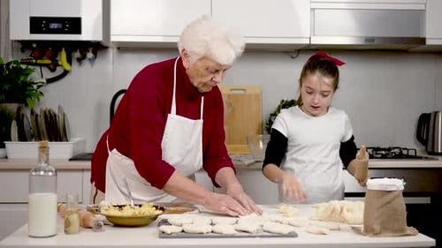 Grandmother Makes Buns From Dough Granddaughter Rolls Pieces with Rolling Pin Preparing Pies at Home