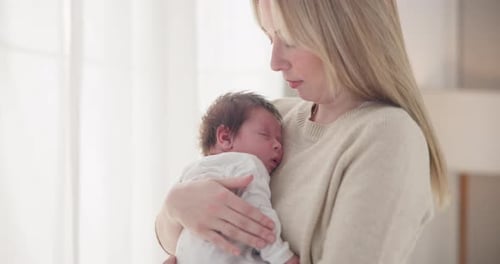 Woman Holding Sleeping Infant in Front of Window