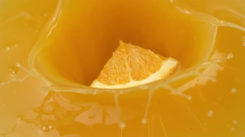 Orange Slice Falling Into Orange Juice in Slow Motion