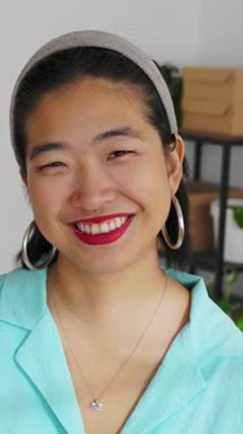 Femme asiatique confiante souriant à la caméra dans un bureau à domicile minimaliste et lumineux