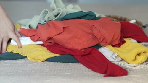 Colorful Clothing Pile on Bed with Assorted Items