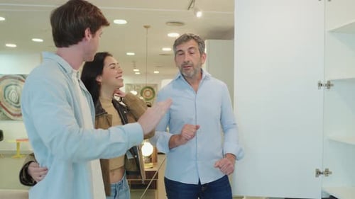 Couple Choosing Furniture Shop Assistant Showing Closet