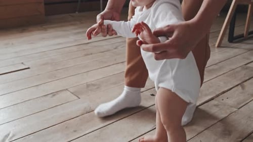 Baby Taking First Steps With Parent's Assistance
