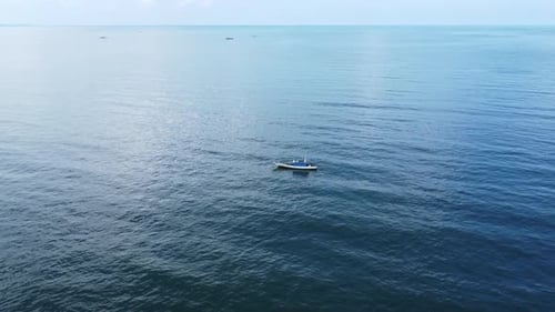 View of a fishing boat sailing on the coast with mountains and clouds in the background