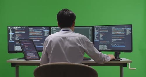 Developer Working With Tablet While Write Code With Multiple Computer Screens In Green Screen Studio
