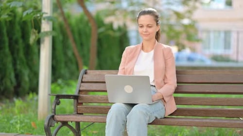 Woman Working on Laptop in City Park