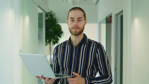 Portrait of a Confident Young Manager Standing in an Office Holding Digital Laptop