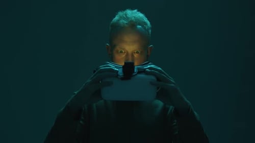 Young Adult Putting on VR Headset in Dim Light