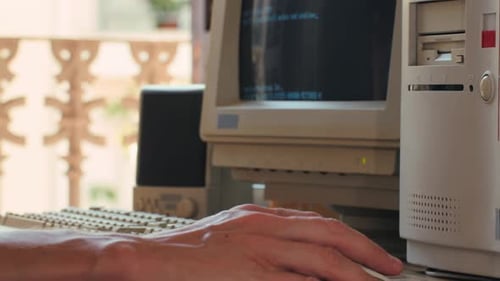 Hombre trabajando y jugando en una computadora retro, ingeniero de TI con una computadora antigua en casa usando una vieja