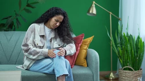 Woman Massaging Sore Knee on Couch