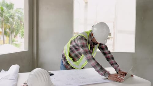 Indian man Wear green reflective vest and safety helmet in houses under construction. Indian archite