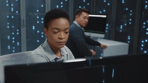 Woman and Man Work in Dark Data Center