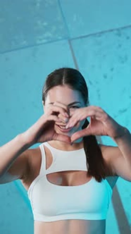 Retrato de una joven y enérgica chica de fitness con top blanco y pantalones cortos negros haciendo calentamiento, respirando hondo
