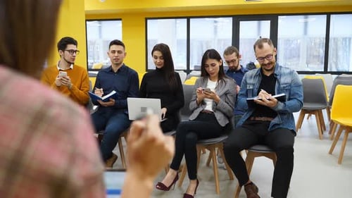 Young Adults Listen to Presentation in Bright Office