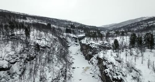 Dramatic Aerial View Of A Frozen River Carving Through Mountains