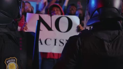 Protesters Stand Behind Police Officers at Night