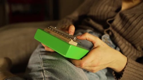 Woman's Hands Softly Strumming Green Kalimba Generating Soothing Tones in Tranquil Indoor