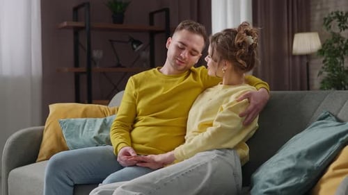 Romantic Couple Cuddling and Talking on Living Room Sofa