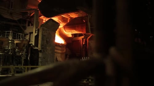 Fiery molten metal pouring in an industrial foundry, captured in vivid detail against dark surroundi