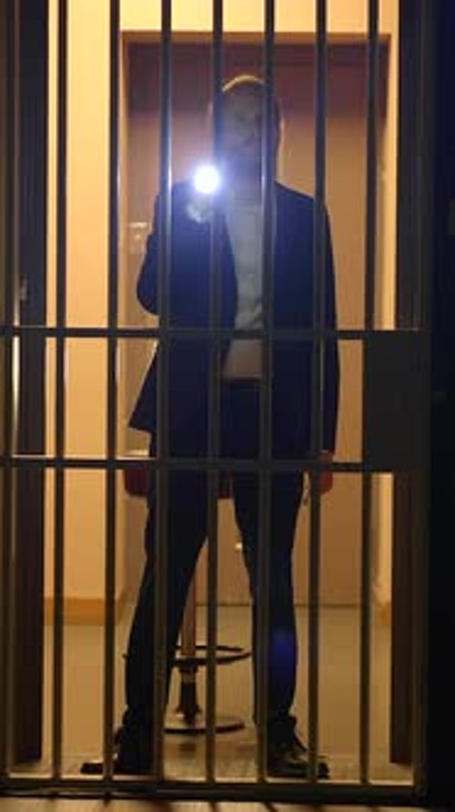 Un personnage mystérieux en prison utilise une lampe de poche pour renforcer l'intrigue et la profondeur de la scène