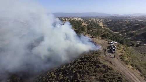 Fire trucks sit atop a burning ridge
