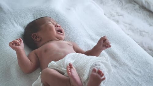 Crying Baby Lying on a White Blanket