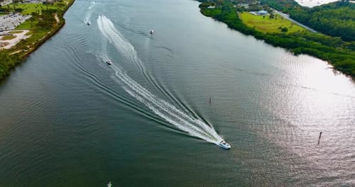 Few motor boats are on the water. Drone footage descending above the river on sunny day.