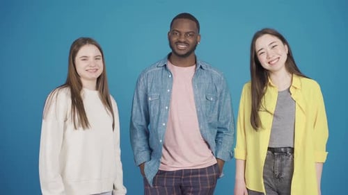 Three Young Adults Smiling on a Blue Background