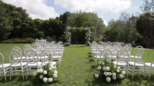 Outdoor Wedding Ceremony Setup with White Chairs and Flowers
